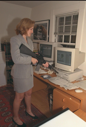 A women pointing a gun at a computer.